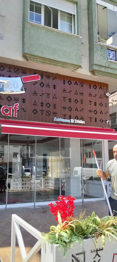 Personel teleskopik aparatla dükkân vitrin camını temizlerken