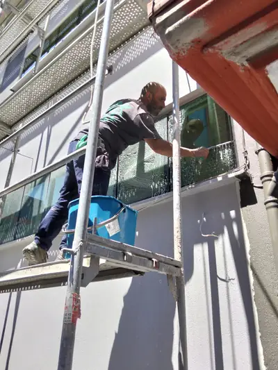 Personel iskele üzerinde cephe camını temizlerken